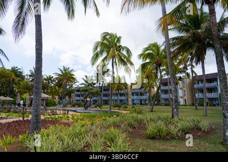 Le Morne, Maurice - 12 mai 2024 : un complexe en bord de mer avec des palmiers et un aménagement paysager soigné sous un ciel partiellement nuageux à Maurice Banque D'Images
