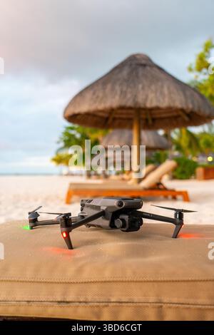 Le Morne, Maurice - 12 mai 2024 : le drone DJI Mavic 3 préparé pour le vol sur le salon de plage sous parasols tropicaux Banque D'Images