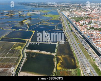 Plan aérien d'étangs salants géométriques avec autoroute et une partie d'Aveiro, Portugal en arrière-plan Banque D'Images
