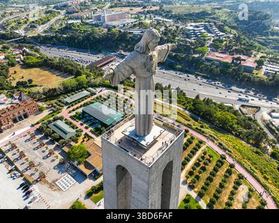 Almada, Portugal - 14 mai 2024 : vue aérienne de l'imposant monument du Christ Roi entouré de verdure et de routes Banque D'Images