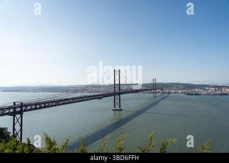 Vue imprenable sur le pont du 25 avril de Lisbonne jetant de l'ombre sur la surface de la rivière Banque D'Images