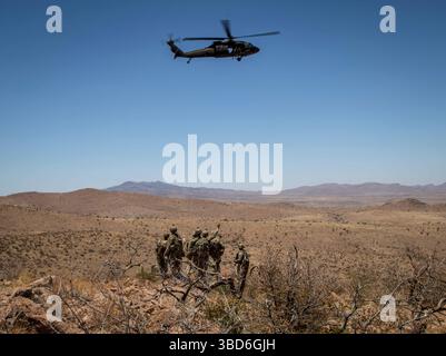 Les soldats américains de la 76th Engineer Company, affectés à la joint Task Force-Southern Border, saluent un hélicoptère UH-60 Black Hawk de l'armée américaine affecté à la 1st combat Aviation Brigade, 1st Infantry Division, lors d'une mission aérienne pour livrer des panneaux de la zone de défense nationale du Nouveau-Mexique (NMNDA) près d'Antelope Wells, Nouveau-Mexique, le 20 mai 2025. Les matériaux ont été fournis par livraison aérienne en raison du terrain austère limitant les manœuvres au sol. Sous la direction du US Northern Command, la joint Task Force–Southern Border aligne les efforts pour sceller la frontière sud et repousser les activités illégales et est responsable de la pleine scal Banque D'Images
