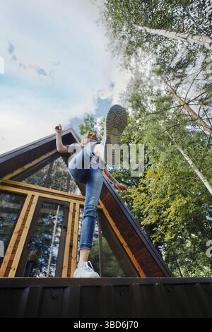 Joyeuse femme saute de la véranda de la cabine a-frame, vue en angle bas Banque D'Images
