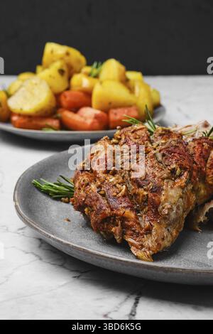 Vue rapprochée de la viande d'épaule d'agneau tirée cuite au four avec pomme de terre et carotte sur une table en marbre Banque D'Images