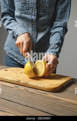Vue rapprochée des mains féminines coupant le citron pour la sauce Banque D'Images