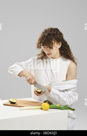 Jeune femme prenant des graines d'avocat avec un couteau Banque D'Images