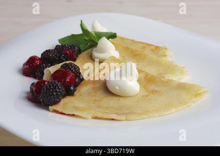 Portion sur de fines crêpes avec du fromage à la crème sucré et des baies Banque D'Images