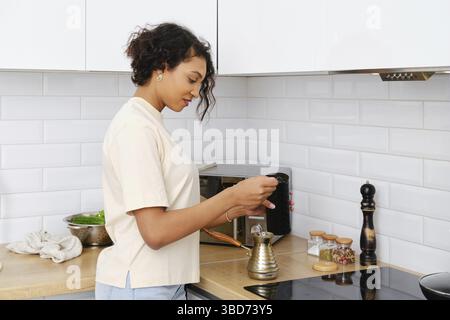 Femme afro-américaine somnolente qui fait du café moulu chez elle dans une crique turque Banque D'Images