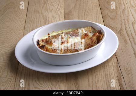 Crêpes frites farcies au jambon et recouvertes de fromage fondu sur une table en bois Banque D'Images