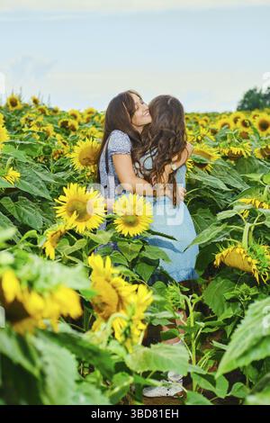 Deux amies se embrassent sur le champ de tournesol Banque D'Images