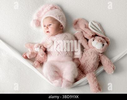 Photoshoot studio d'Une petite fille nouveau-né sur Une balançoire avec Un lapin jouet Banque D'Images