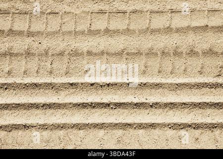 Traces de pneu dans le sable. Marques du véhicule sur sol beige. Détail texturé tout-terrain. Fond de voyage en plein air. Motif désert grunge. Nature et aventure. Banque D'Images