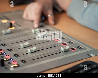 Un technicien du son ajuste habilement les niveaux audio sur une console de mixage dans un studio d'enregistrement. L'environnement est axé sur l'amélioration de la qualité sonore du Banque D'Images