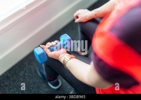 Main de la femme tenant un haltère pour faire des exercices de force et renforcer les muscles du bras. Banque D'Images