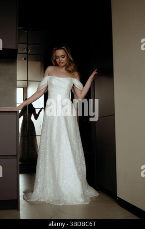 Robe de mariée élégante présentée dans un intérieur minimaliste avec modèle en pose chic Banque D'Images