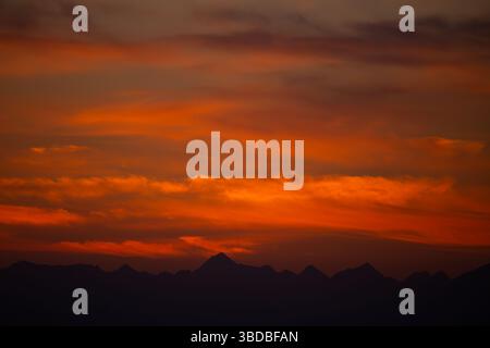 Coucher de soleil majestueux avec rouge et orange vif sur les silhouettes de montagne Banque D'Images