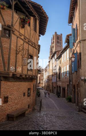 Les maisons à pans de bois et les façades en briques hautes créent une rue pittoresque étroite dans la vieille ville d'Albi France sous un ciel bleu clair d'été. Banque D'Images