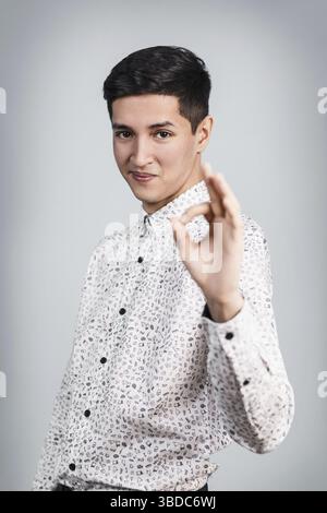 Jeune homme séduisant montre OK signe sur l'arrière-plan gris Banque D'Images