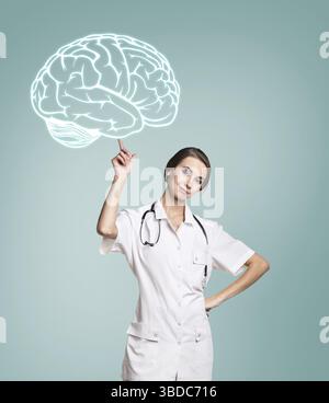 Jeune médecin féminin dans le toucher uniforme peint cerveau sur fond vert Banque D'Images