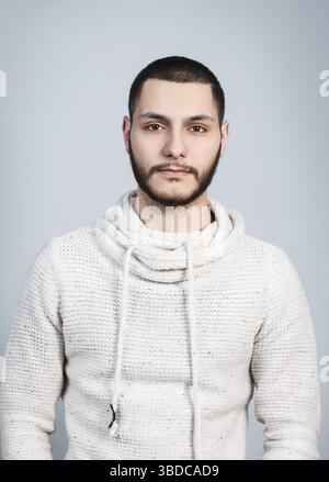 Jeune homme beau avec un visage sérieux sur le fond gris Banque D'Images
