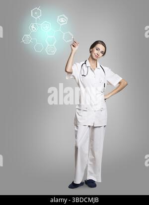 Jeune femme médecin en uniforme touch avec des icônes hexagonales sur fond gris Banque D'Images