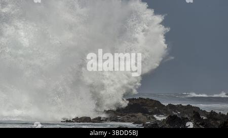 Une vague massive s'écrase contre les rochers du rivage à Storms River Mouth et crée une grande éclaboussure Banque D'Images