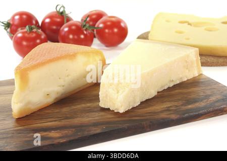 Une sélection de différents morceaux de fromage avec des tomates sur une planche de bois Banque D'Images