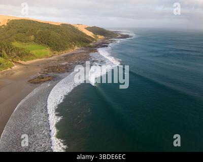 Vue aérienne des vagues de surf et des surfeurs à Ahipara Bay à l'extrémité sud de la plage de Ninety Mile à Northland, Nouvelle-Zélande Banque D'Images