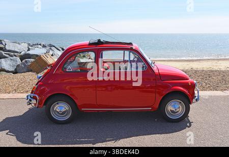 Voiture classique Rouge Fiat 500 avec panier pique-nique garé sur la promenade du front de mer. Banque D'Images