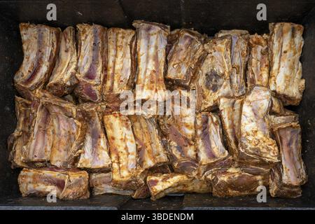 Les côtes courtes de bœuf assaisonnées et marinées sont placées dans un grand bol en métal noir, préparation pour une partie barbecue avec de nombreux invités, vue de dessus Banque D'Images