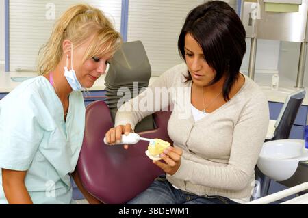 Assistant dentaire expliquant au patient se brosser les dents, dentiste, patient, brosse à dents électrique, brossage des dents Banque D'Images