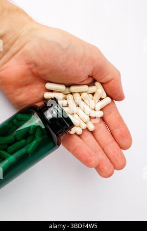 Capsules tenant dans la main versées à partir de la bouteille de supplément. Banque D'Images