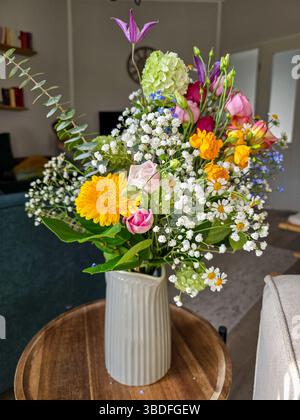 bouquet de fleurs mélangées dans un vase en céramique rayé décore un espace de vie confortable, capturant la chaleur et la gaieté des fleurs fraîches à l'intérieur Banque D'Images