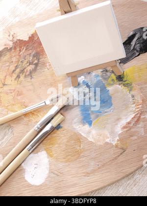 Palette de peinture avec des pinceaux et une petite toile Banque D'Images