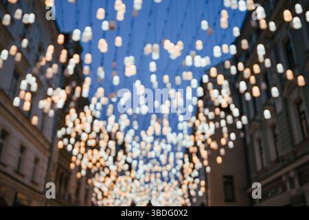 Des rangées de lanternes brillantes pendent au-dessus d'une rue de ville, arrière-plan flou flou, ambiance nocturne, éclairage urbain Banque D'Images