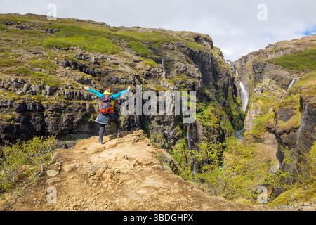 Cascade de Glymur à Hvalfjordur, Vesturland, Islande vue sur le paysage avec randonneur femme touriste debout sur le bord sur le ravin. Banque D'Images