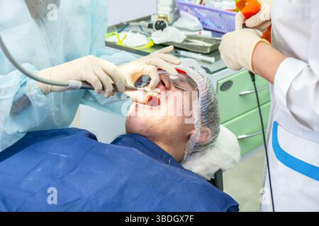 Les professionnels dentaires effectuent une intervention sur un patient tout en assurant la sécurité et le confort en milieu clinique Banque D'Images