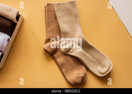 Paire de chaussettes côtelées confortables de couleurs beige et marron clair, affichées sur fond jaune, mettant en valeur la texture et la chaleur pour la mode et le confort. Banque D'Images