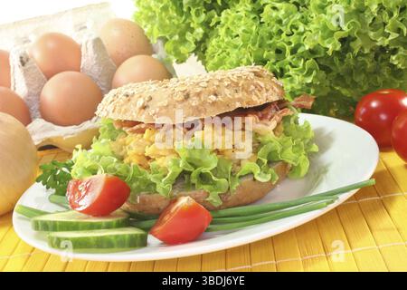 Le seigle bagel avec salade, œufs brouillés et bacon Banque D'Images