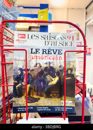 Dijon, France - 12 avril 2025 : couverture de les saisons dâAlsace numéro 91 intitulé le Reve Americain American Dream Translated montré dans un présentoir en fil rouge dans un kiosque, avec une peinture de style vintage et des titres Banque D'Images
