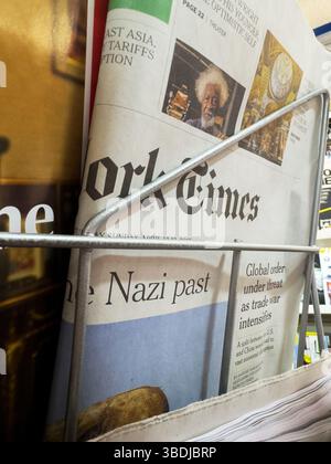 Dijon, France - 12 avril 2025 : le journal plié du New York Times se trouve dans un support métallique d'un kiosque, montrant les gros titres sur l'histoire nazie et les menaces pour l'ordre mondial à côté d'images en couleur Banque D'Images