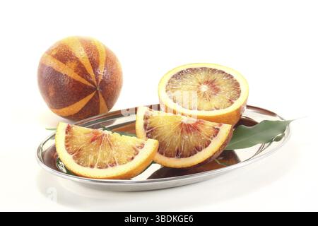 Deux oranges sanguines rouges-jaunes fraîches avec des feuilles sur un fond clair Banque D'Images