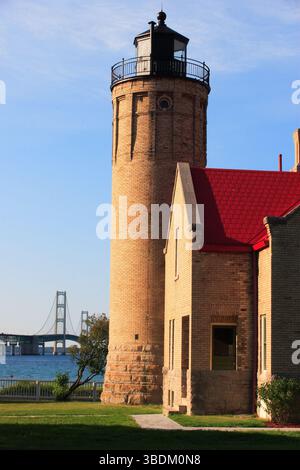 Phare en briques près de l'eau bleue avec pont en arrière-plan Banque D'Images