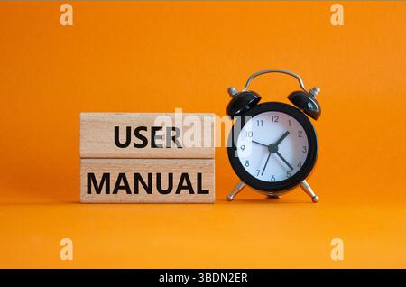 Symbole du manuel de l'utilisateur. Mots conceptuels Manuel de l'utilisateur sur blocs de bois. Beau fond orange avec réveil. Concept du manuel d'utilisation et de l'entreprise. Copier s Banque D'Images