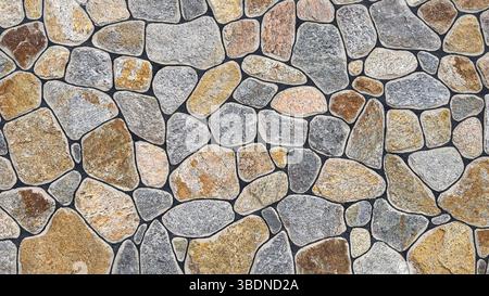 Un grand mur fait de pierres de granit naturel de différentes tailles et couleurs de texture grise. Banque D'Images