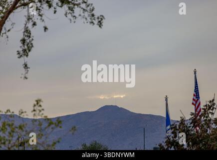 Ciel nocturne au-dessus d'une chaîne de montagnes de l'Arizona avec la lumière subtile du coucher du soleil, encadrée par des arbres et des drapeaux américains et d'état ondulant doucement au premier plan. Banque D'Images