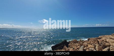 La lumière du soleil scintille sur l'océan sous un ciel bleu clair Banque D'Images