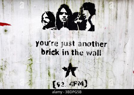Pochoir Floyd rose avec la lyrique « une autre brique dans le mur » et le logo 92,4 FM sur un mur de graffitis à Dhaka. Banque D'Images