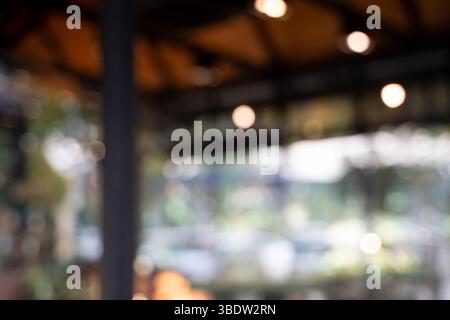 Un café de café flou avec arrière-plan bokeh image floue de café extérieur ou d'un restaurant avec un éclairage chaud et un plafond en bois, créant confortable Banque D'Images