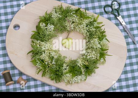 couronne florale avec fleurs de sureau et fruits de cornbeam sur une planche de bois Banque D'Images